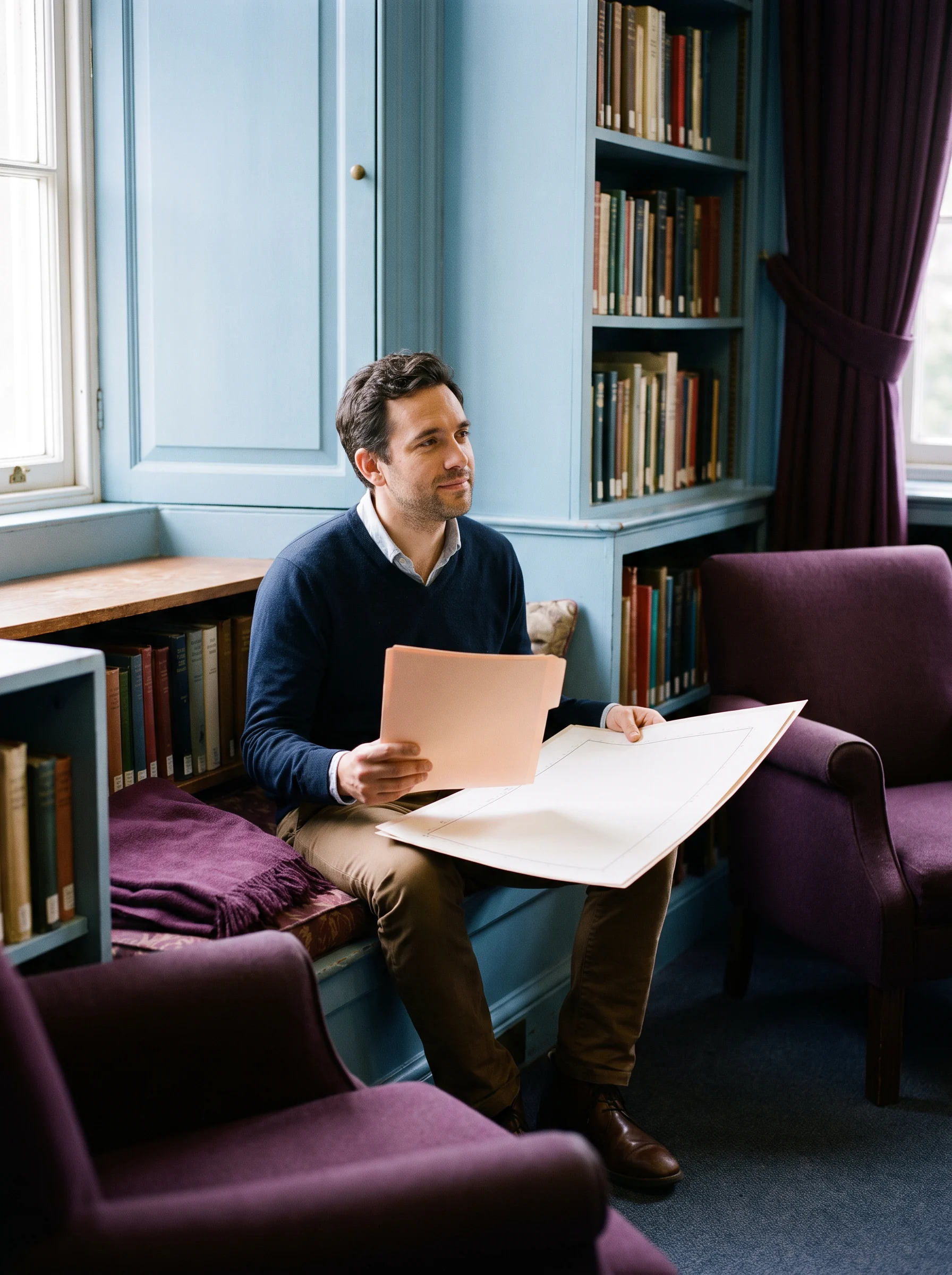 A person sitting at an open table in a library reviewing documents